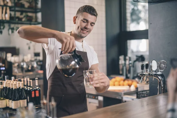 Barista sonriente mirando confiado mientras vierte café fresco — Foto de Stock