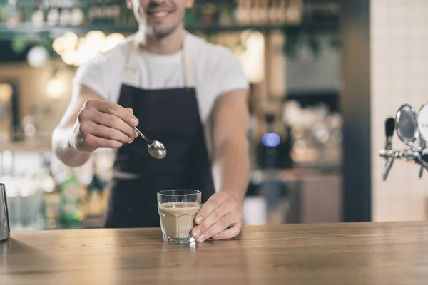 Barista sonriente sosteniendo cuchara cerca del vaso de cacao — Foto de Stock