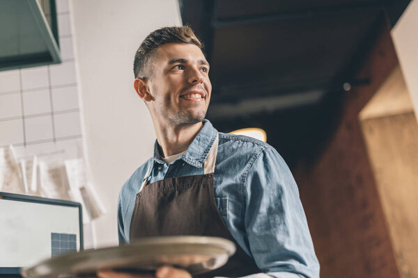 Smiling waiter with tray looking into the distance