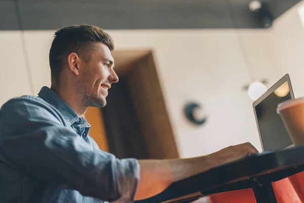 Nahaufnahme eines fröhlichen Mannes mit seinem modernen Laptop — Stockfoto