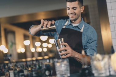 Pozitif genç adam kokteyl shaker içine sıvı döküyor