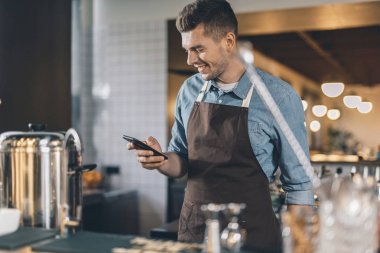 Pozitif garson akıllı telefon bakıyor ve gülümseyen