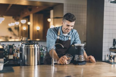Kendinden emin barista gülümseme ile damla dekanter bakarak