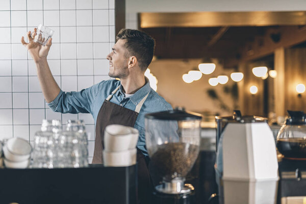 Энтузиастичный бариста проверяет стекло, поставив его
