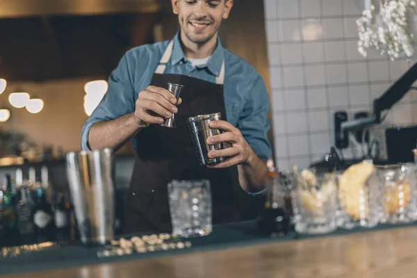 Cantinero sonriente añadiendo ingredientes al cóctel — Foto de Stock