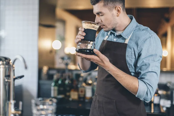 Концентрированный бариста нюхает кофе с закрытыми глазами — стоковое фото