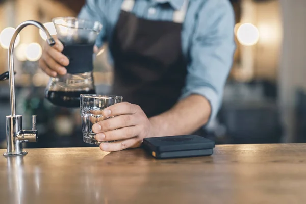 Hand putting glass on the bar counter and holding drip decanter — Stock Photo, Image
