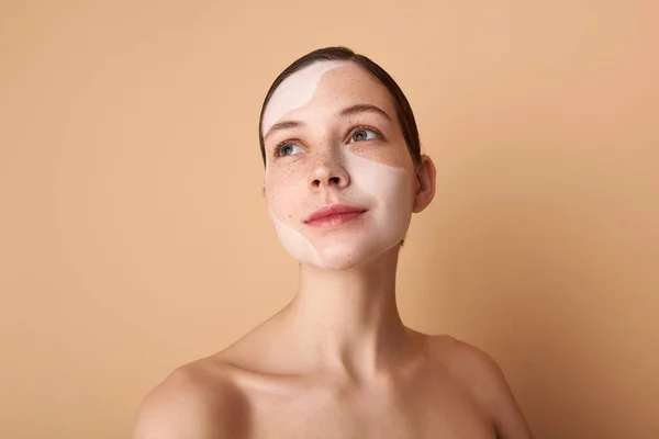 Linda chica con máscara blanca en su cara de pie sobre fondo beige —  Fotos de Stock