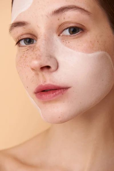 Jolie fille avec masque blanc sur le visage debout sur fond beige — Photo