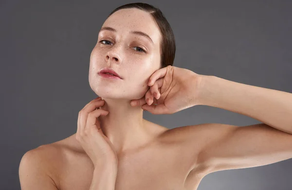 Attractive young woman with freckles touching her face and neck — Stock Photo, Image