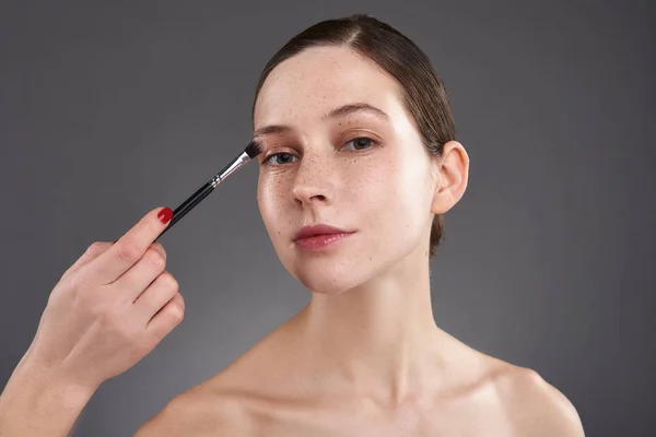 Makeup artis menerapkan eyeshadow pada kelopak mata wanita muda — Stok Foto