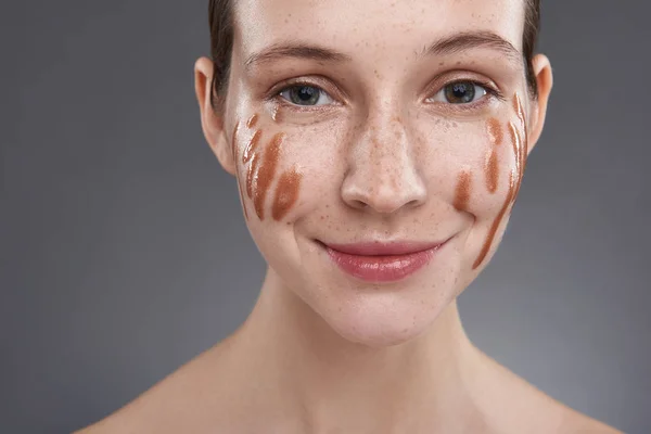 Jolie fille avec du brillant à lèvres doré sur son visage regardant la caméra et souriant — Photo