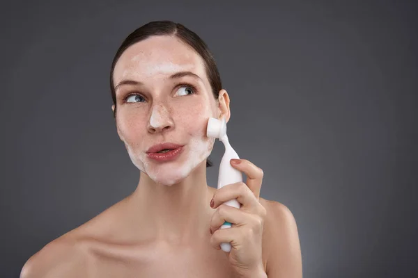 Menina bonita usando escova de limpeza de poros após o banho — Fotografia de Stock