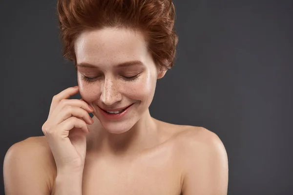 Schattig roodharige meisje met gesloten ogen staande tegen grijze achtergrond — Stockfoto