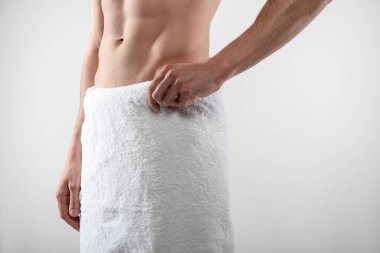 Mükemmel karın kasları olan genç bir adam beyaz arka planda duruyor.