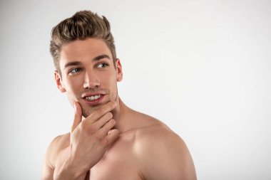 Beyaz arka plan aleyhine duran şık saç kesimi ile çekici genç adam