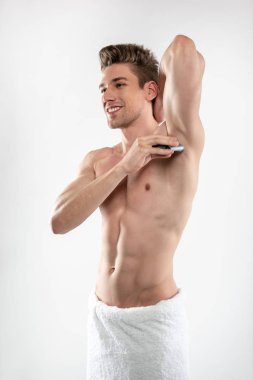 Koltuk altı üzerinde antiperspirant uygulayan mükemmel vücut ile Joyful yakışıklı adam