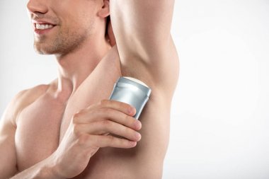 Koltuk altı üzerinde antiperspirant uygulayan neşeli genç adam