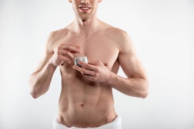 Kozmetik krem kavanoz tutan kaslı vücut ile neşeli genç adam