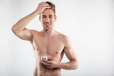 Kozmetik krem kavanoz tutan mükemmel kaslı vücut ile neşeli genç adam
