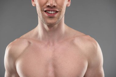 Mavi-gri arka plan aleyhine ayakta sakallı gülümseyen genç adam