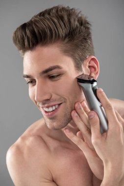 Joyful yakışıklı adam elektrikli jilet ile tıraş