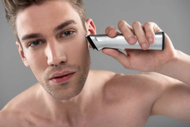 elektrikli ustura ile tıraş yakışıklı genç