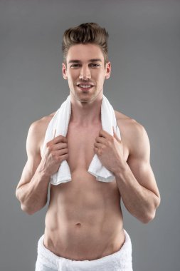 Mavi-gri arka plan aleyhine duran mükemmel vücut ile çekici genç adam