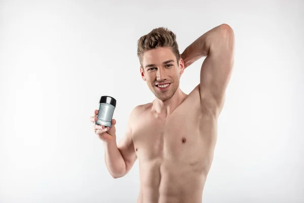 Joven alegre con cuerpo musculoso perfecto sosteniendo antitranspirante — Foto de Stock