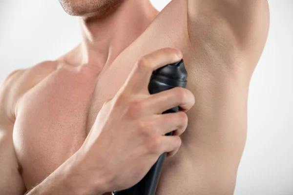 Jonge man met gespierd lichaam met behulp van deodorant spray — Stockfoto