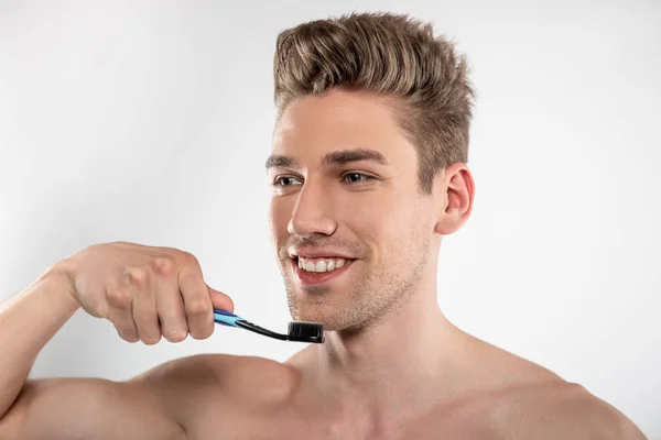 Pohledný mladý muž s strniště, držící zubní kartáček — Stock fotografie