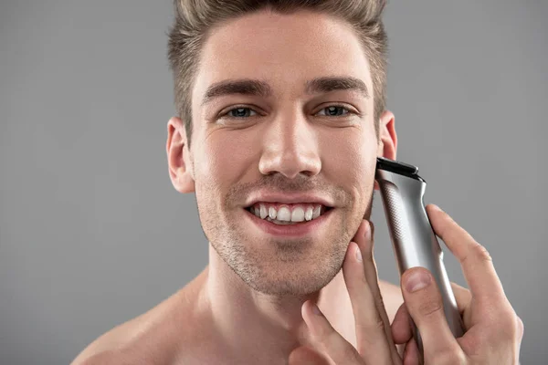 Chico guapo alegre afeitándose con afeitadora eléctrica —  Fotos de Stock