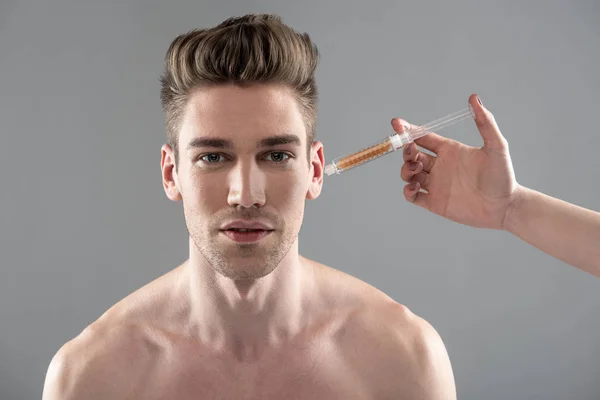 Mão esteticista aplicando soro vitamínico na bochecha do jovem — Fotografia de Stock