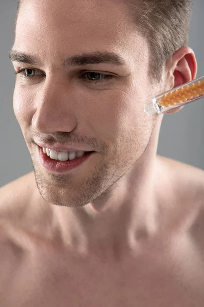 Esteticista aplicando soro vitamínico na bochecha do jovem bonito — Fotografia de Stock
