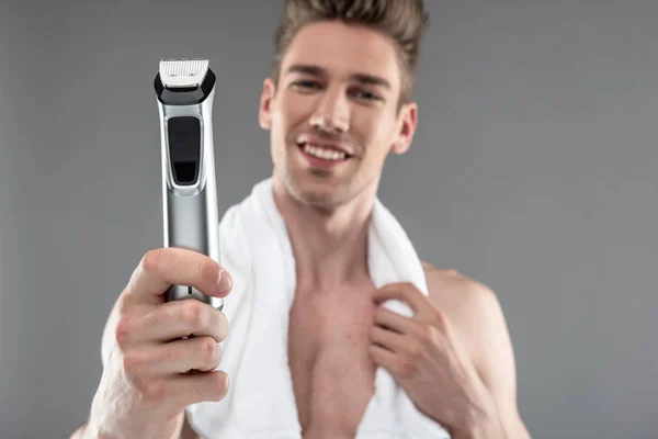 Handsome young man with towel holding electric razor — Stock Photo, Image
