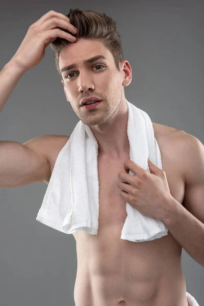 Ελκυστικός νέος άντρας με πετσέτα που προσαρμόζει τα μαλλιά του — Φωτογραφία Αρχείου