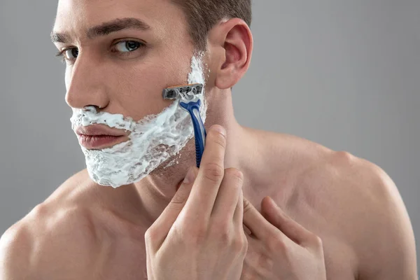 Tek kullanımlık jiletle tıraş olan yakışıklı genç adam — Stok fotoğraf