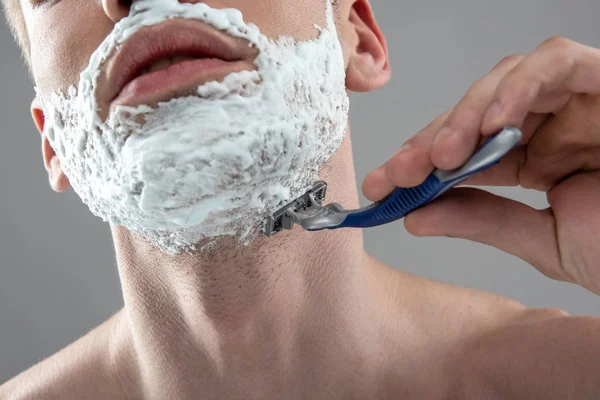 Młody człowiek golący swój zarost brzytwą jednorazową — Zdjęcie stockowe
