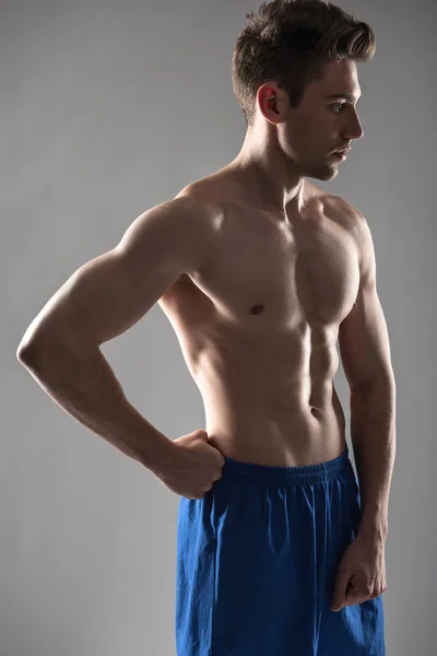 Mavi-gri arka plan karşı duran mükemmel vücut ile yakışıklı genç adam — Stok fotoğraf