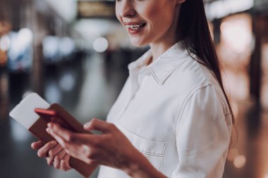 Neşeli kadın havaalanında akıllı telefon kullanıyor