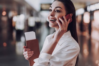 Kadın uçuştan önce telefonla konuşurken gülüyor.