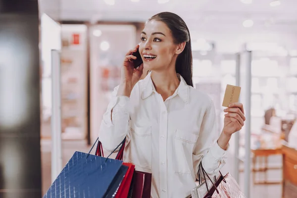 Feliz jovem está falando ao telefone enquanto faz compras — Fotografia de Stock