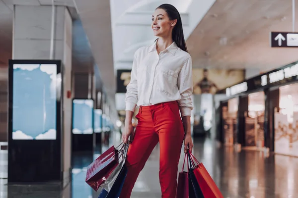 Encantada joven mujer está a la espera de vuelo con compras — Foto de Stock