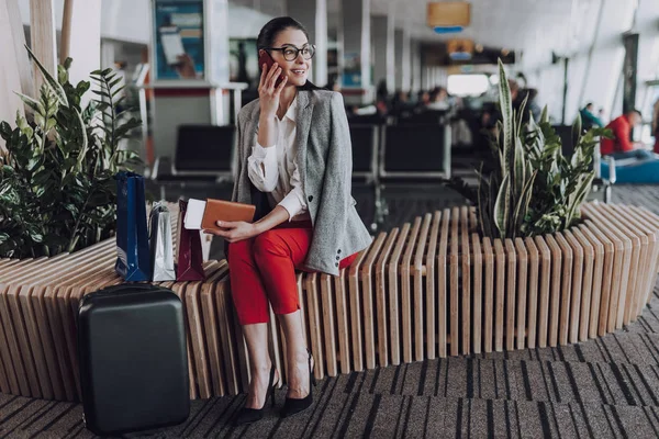 Mujer alegre está hablando por teléfono mientras espera el avión —  Fotos de Stock