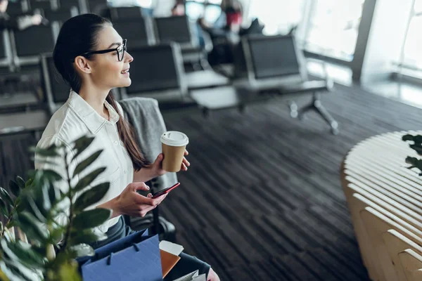 Empresária alegre está relaxando com café e telefone antes da partida — Fotografia de Stock