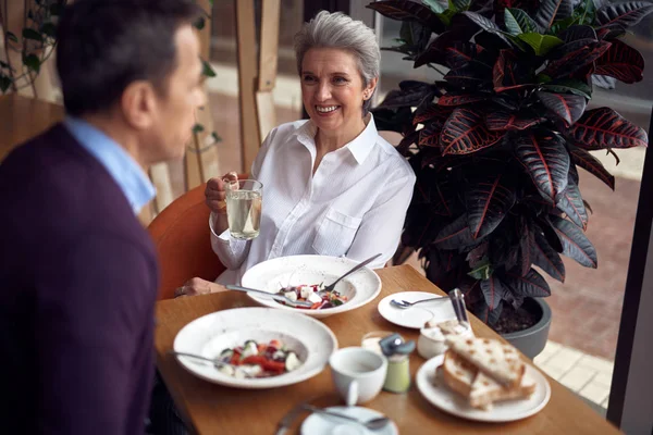 Gray haired smiling woman with cup of water in cafe — Stock Photo, Image