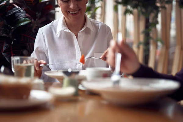 Smiling woman eating salad in cafe with man — Stock Photo, Image