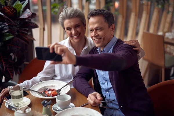 Feliz anciana señora y el hombre haciendo selfie en la cafetería —  Fotos de Stock