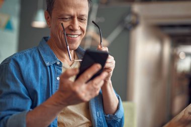 Gülümseyen yaşlı adam cep telefonumesajlaşma