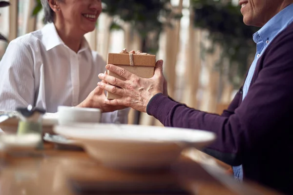 Aged man giving present box to happy lady — Stock Photo, Image